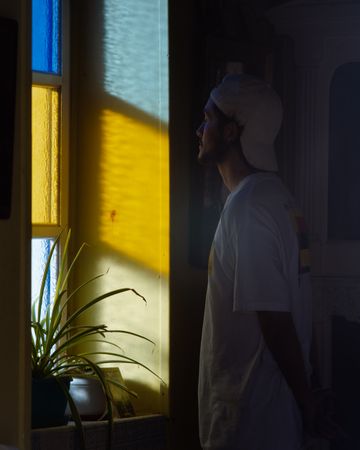 Side view of young man in light shirt standing near colorful window