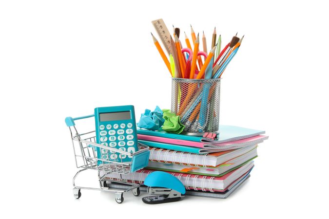 Shopping cart with pile of notebooks, calculator and pencils