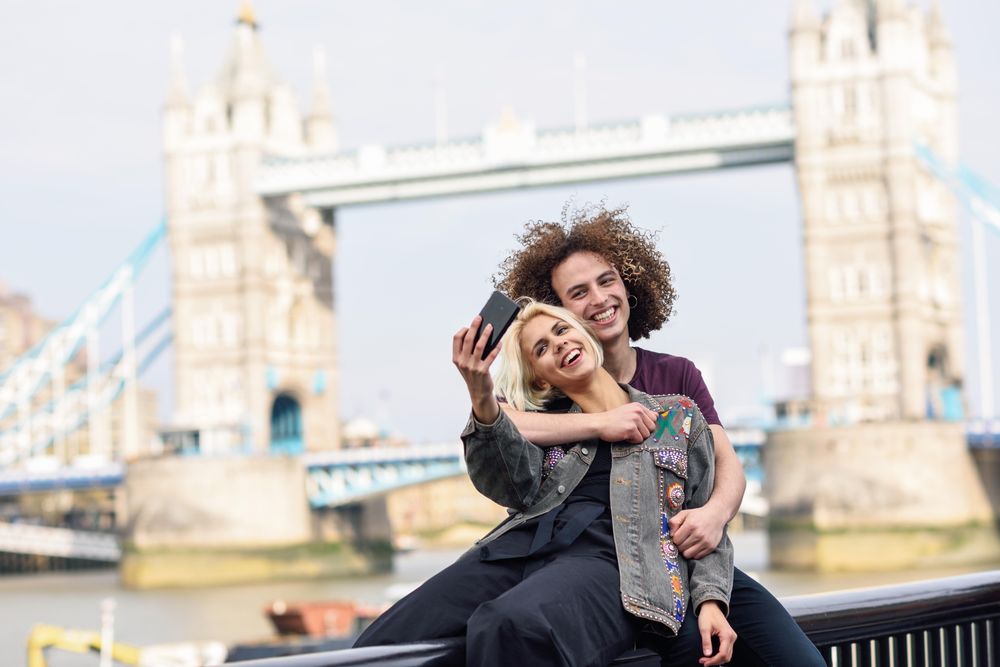 Girlfriend and boyfriend hugging for photo in front of famous British bridge