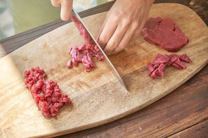 Crop cook chopping meat on wooden board