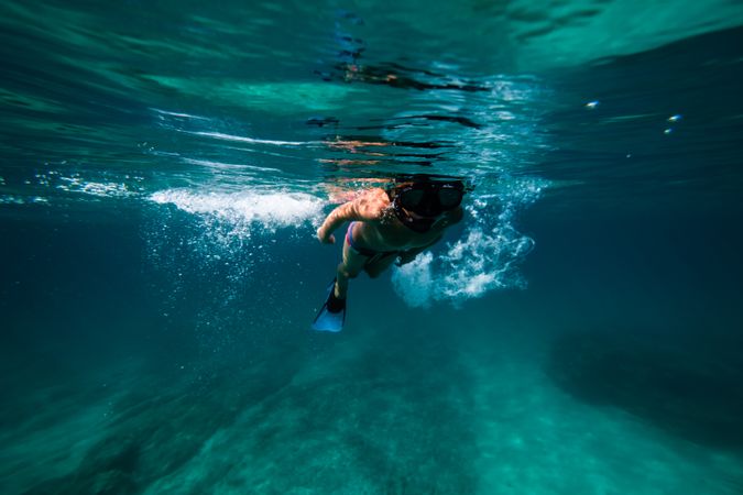 Preteen boy in flippers swimming underwater with splashes
