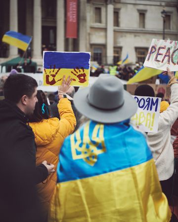 London, England, United Kingdom - March 5 2022: Woman in hat draped in Ukrainian flag