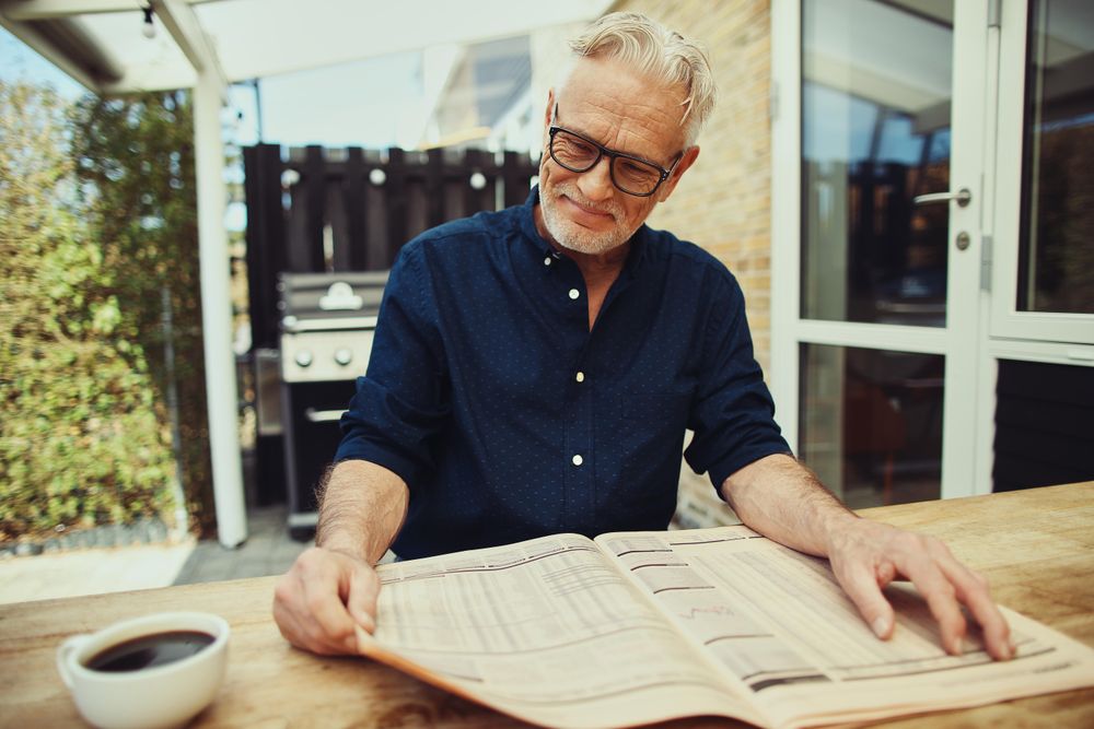 Mature man enjoying reading the newspaper outside