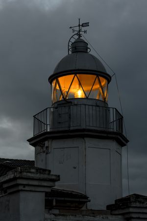 Shining lighthouse against cloudy sky