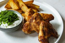 Chicken wings with dip and potato wedges close up