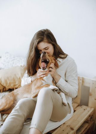 Woman kissing  beagle  dog's head on bed