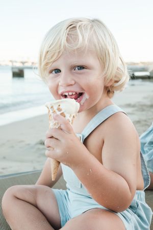Happy child eating ice cream on beach