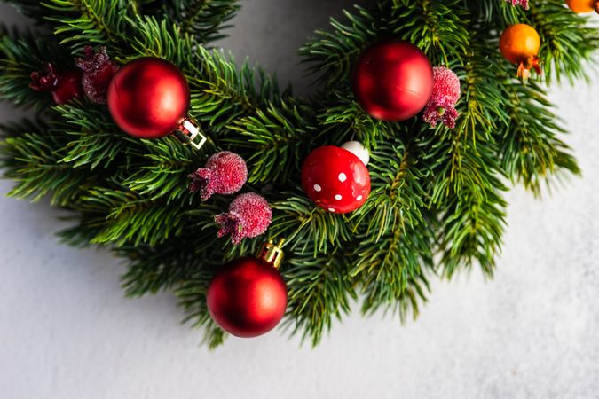 Top view of Christmas wreath with red berries and ornaments on marble counter