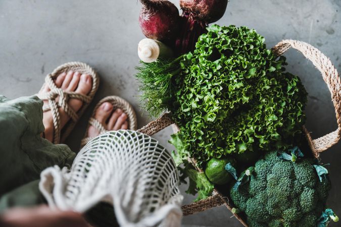 Overhead shot of grocery shopping jute full of fresh produce, with feet, horizontal composition