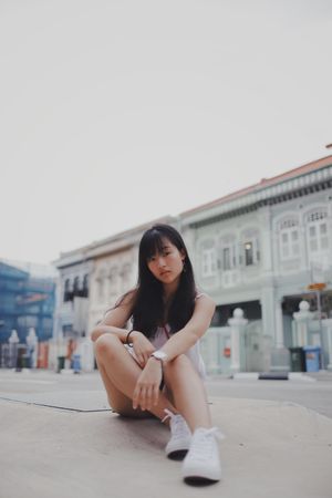 Girl posing on the floor in front of building