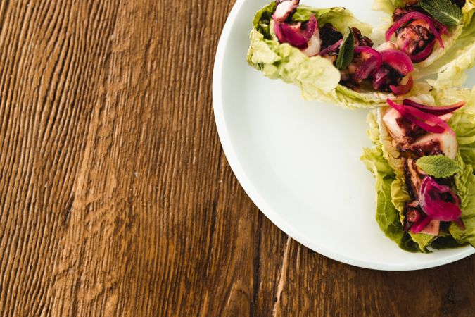 Plate with lettuce wraps on wooden table