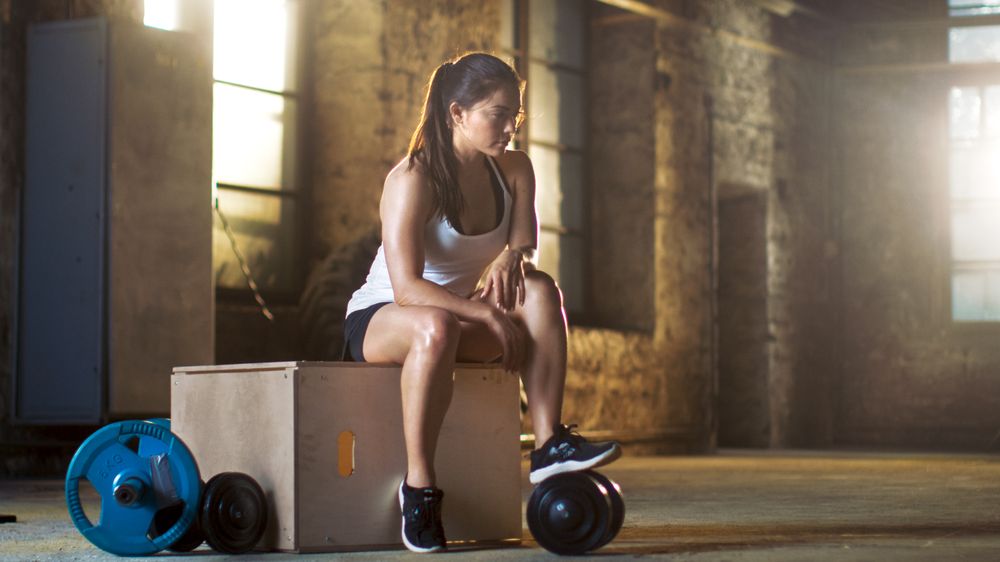 Athletic Woman Relaxes on a Bench After Intensive Cross Fitness Bodybuilding