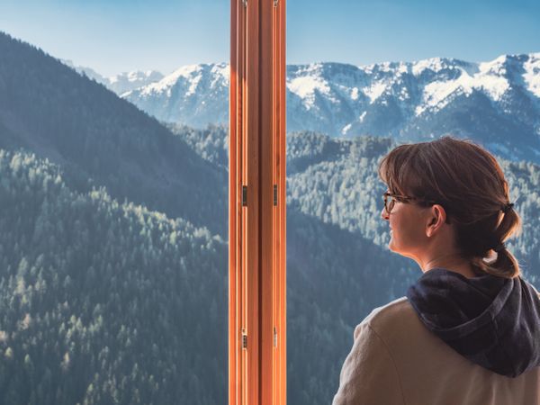 Anonymous woman looking at mountains from window