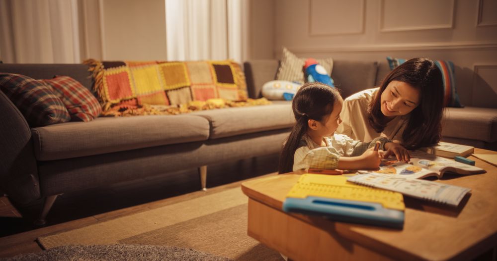 Mother and Cute Little Daughter Drawing together in the Living Room.
