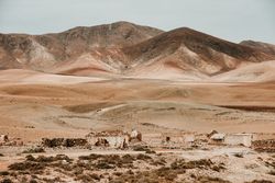 Dilapidated old buildings in mountain desert under cloudy sky