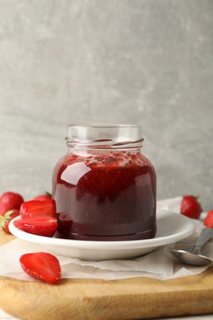 Composition with strawberry jam on wooden table against gray background