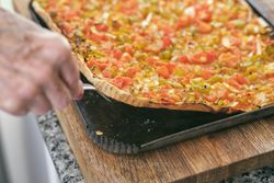 Crop woman serving delicious pizza on wooden board