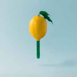 Lemon with ice cream stick on pastel blue background