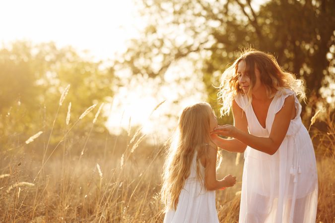 Woman holding a little girls chin in marsh at sunset