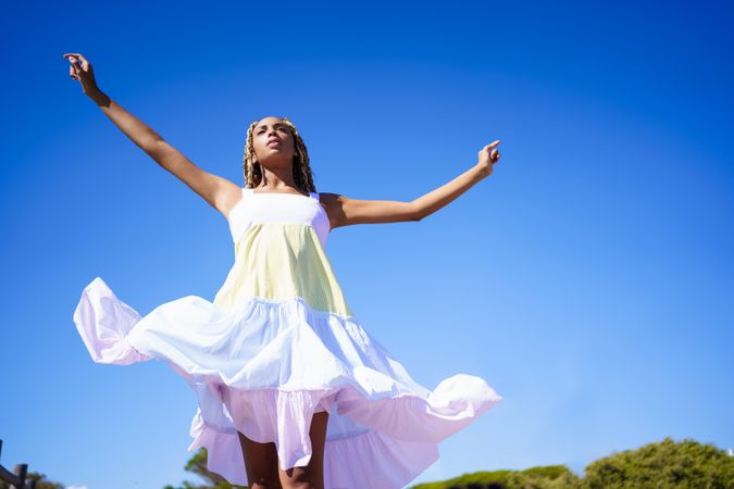 Carefree female spinning in colorful dress on clear day