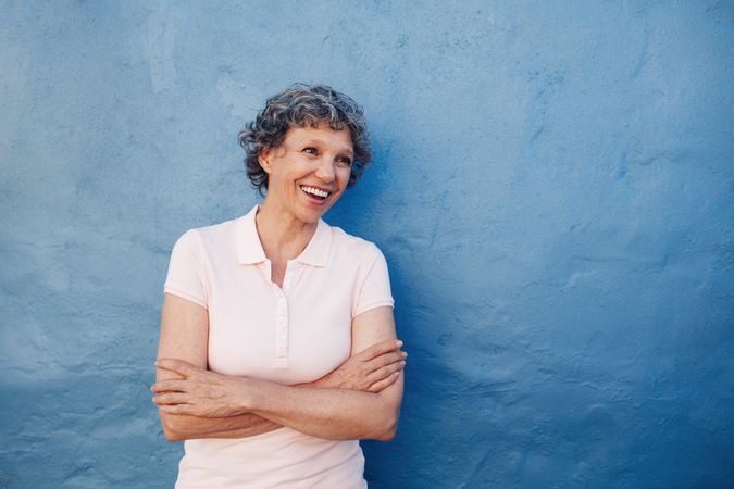 Smiling woman standing with her arms crossed and looking away at copy space