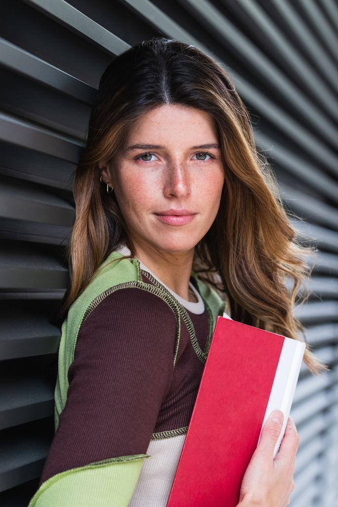 Smiling student reading book on city street