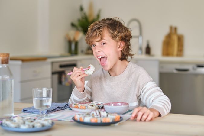 Happy kid enjoying tasty rolls in kitchen at home