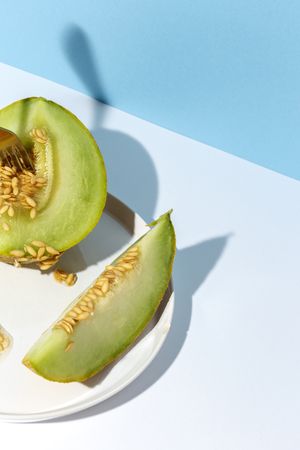 Sliced small melon on plate with spoon and fork