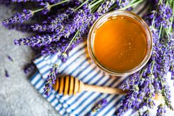 Top view of pot of honey with bunch of lavender with dipper