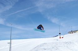 Unrecognizable snowboarder jumping on slope