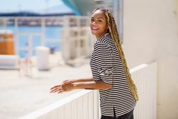 Happy female leaning on railing of the pier looking around