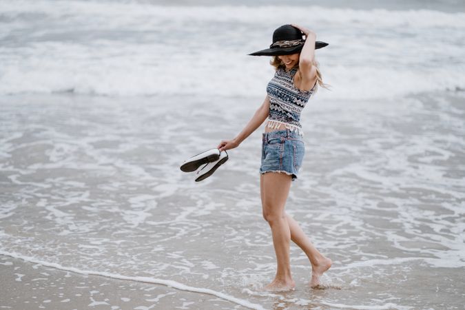 Young female walking barefoot on sandy beach