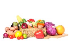 Wicker basket, wood board and vegetables isolated on blank background