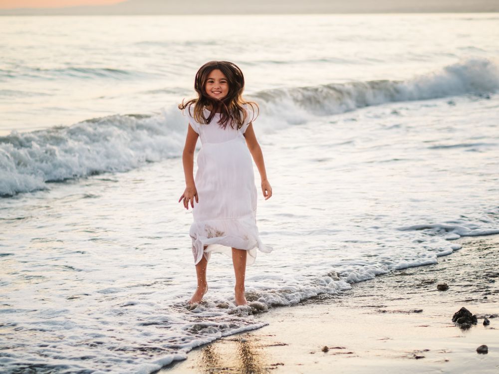 Excited girl running along beach in daylight