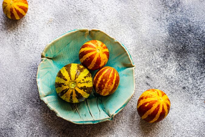 Organic mini melons in teal bowl with copy space