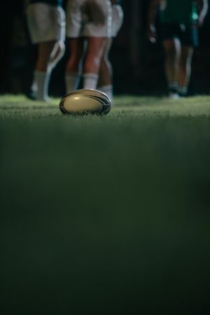 Rugby ball on grass with teams in background