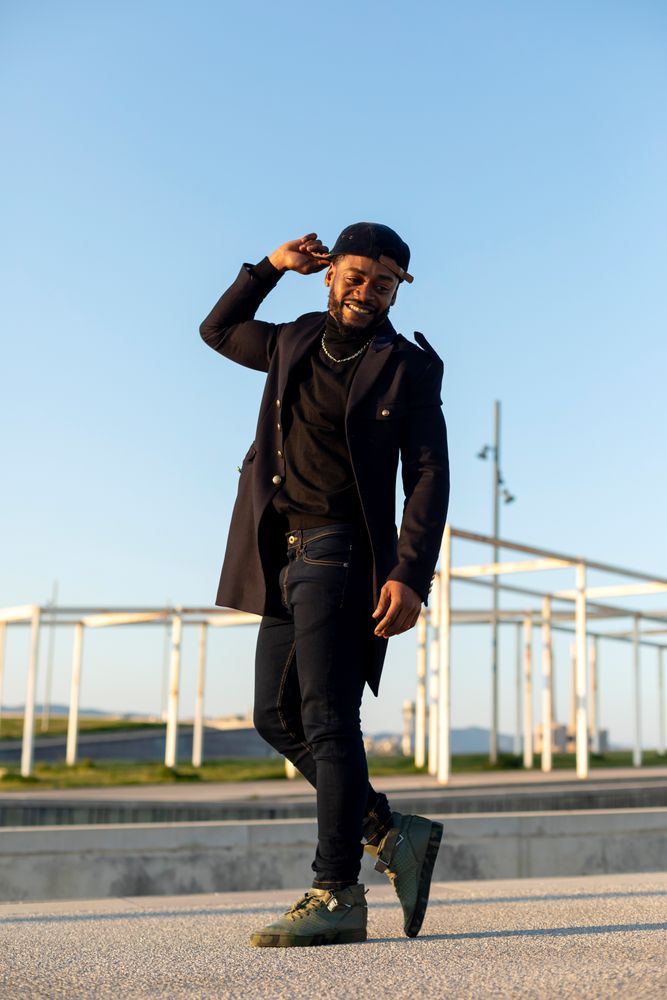 Smiling Black bearded man holding head while turning around on a sunny day