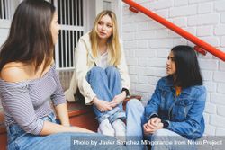 Three women having a conversation on outdoor brick steps 5woq65