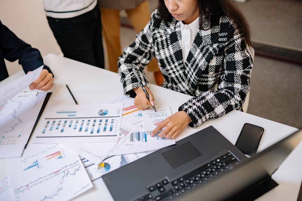 Cropped image of employees sitting at table filled with statistics documents