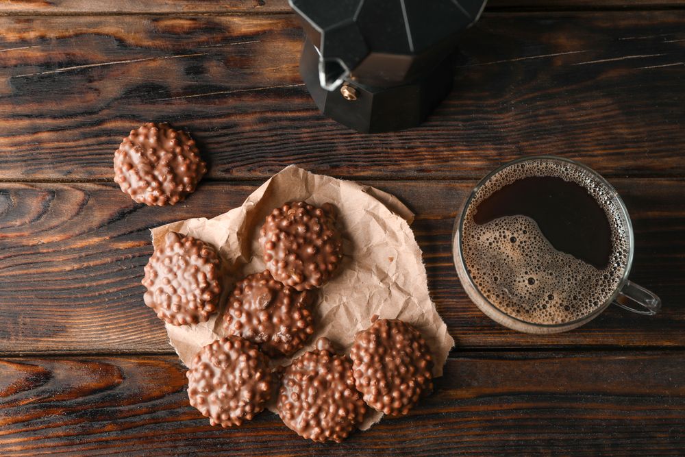 Chocolate cookies and cup of coffee on wooden table, top view