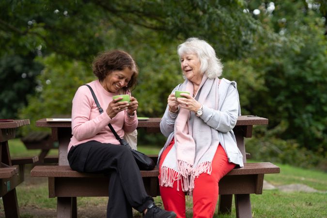 Two older women sitting outside sipping tea