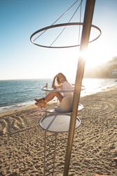Beautiful blonde model sits atop guard tower on beach