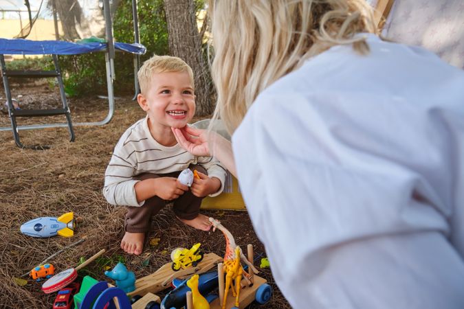 Happy child playing with toys near mother in park