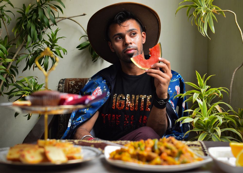 Man with hat eating watermelon at dining table