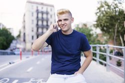 Young blond man using a cell phone on the street