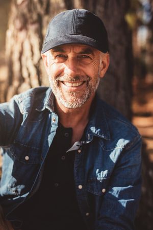 Close up portrait of happy mature man wearing cap looking at camera and smiling