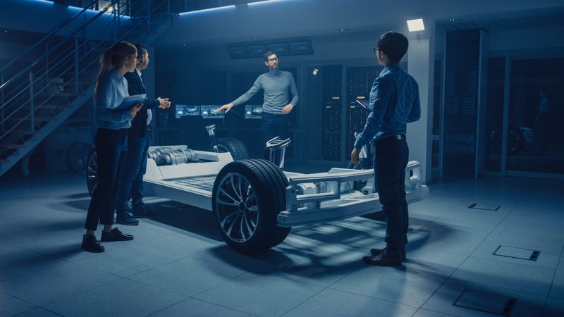 Automobile Engineers Working on Electric Car Platform Chassis, Using Tablet Computers