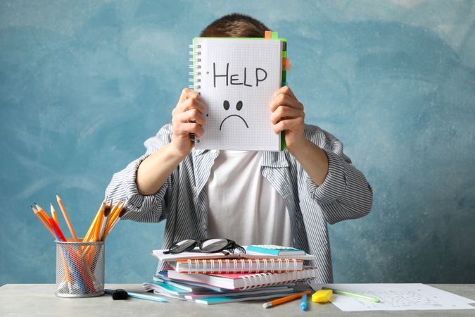 Child holding up plain notebook saying “help”