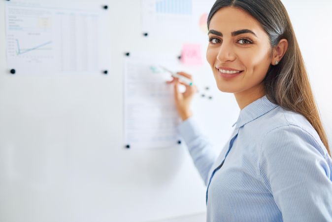 Confident female entrepreneur brainstorming on a dry erase board in bright office