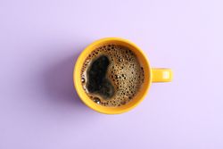 Cup of coffee on color background, space for text